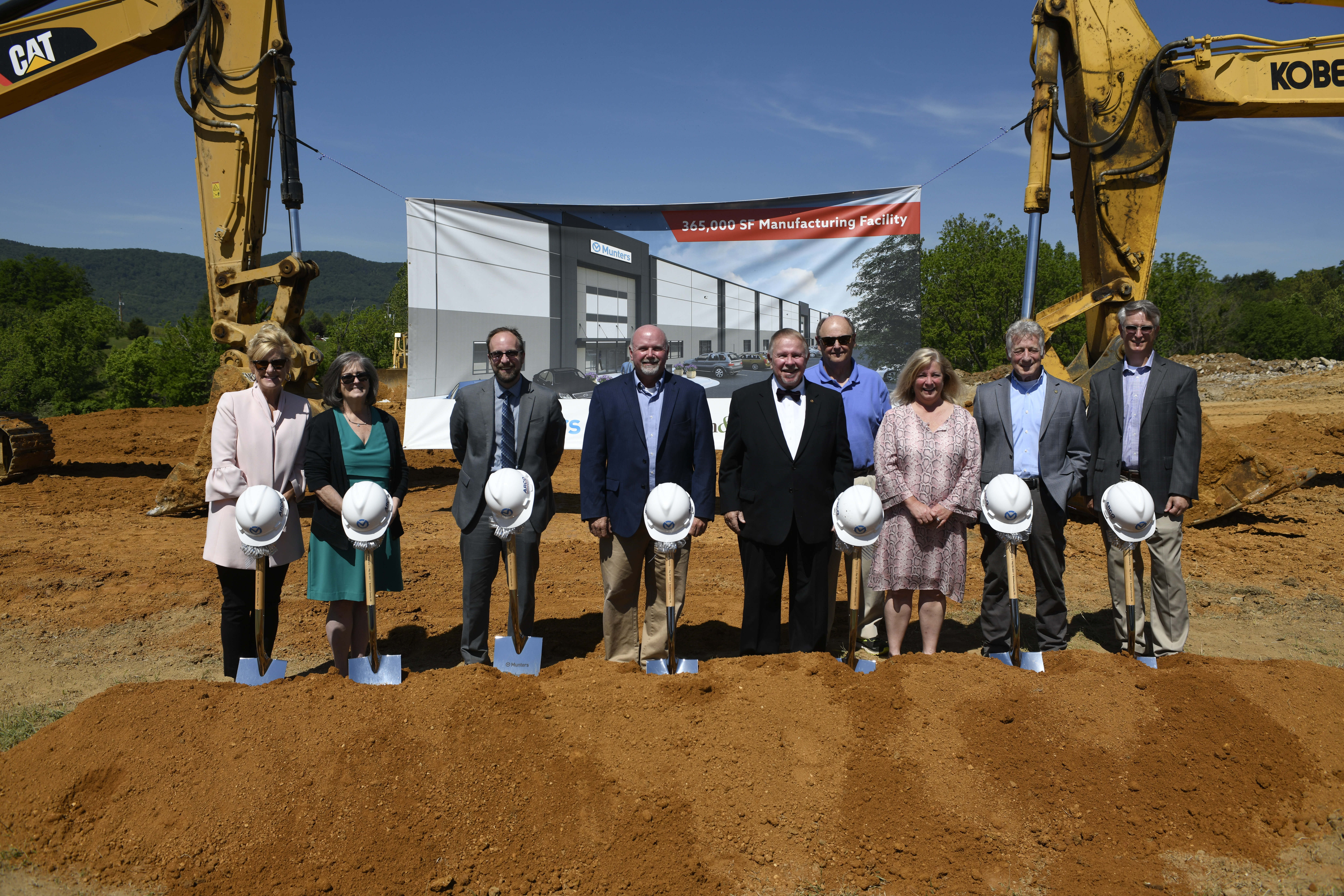 business professionals posing for a groundbreaking ceremony with shovels and hardhats.