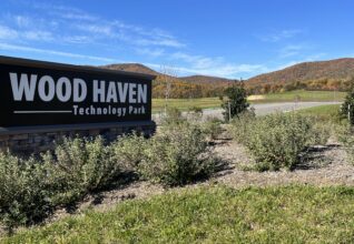Sign that reads "Wood Haven Technology Park" with a blue sky and mountains in the background