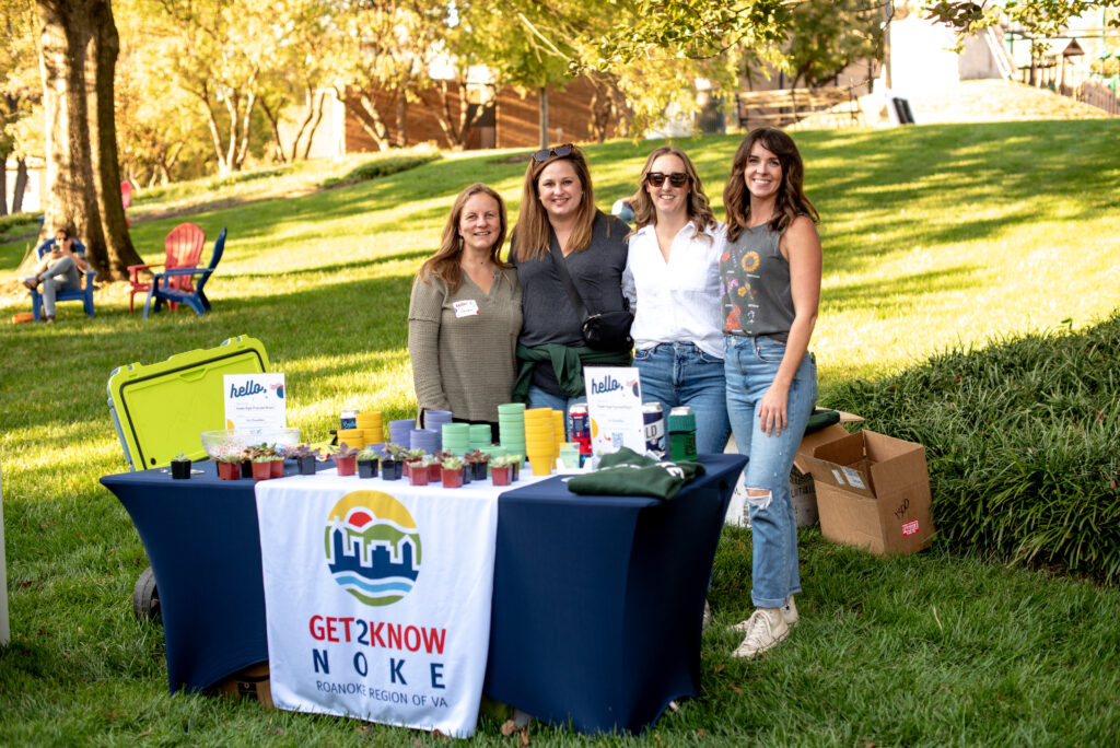 Group of four white women smiling at a table of plants at Roanoke GoFest