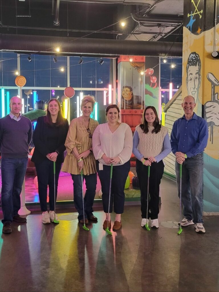 Group of six economic developers  smiling at the camera at a putt-putt golf course.