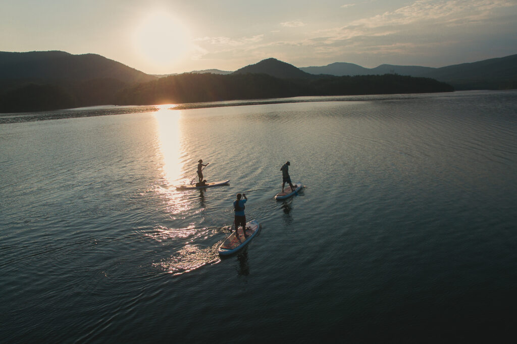 Three people stand-up paddleboarding on Carvins Cove in Roanoke, VA.