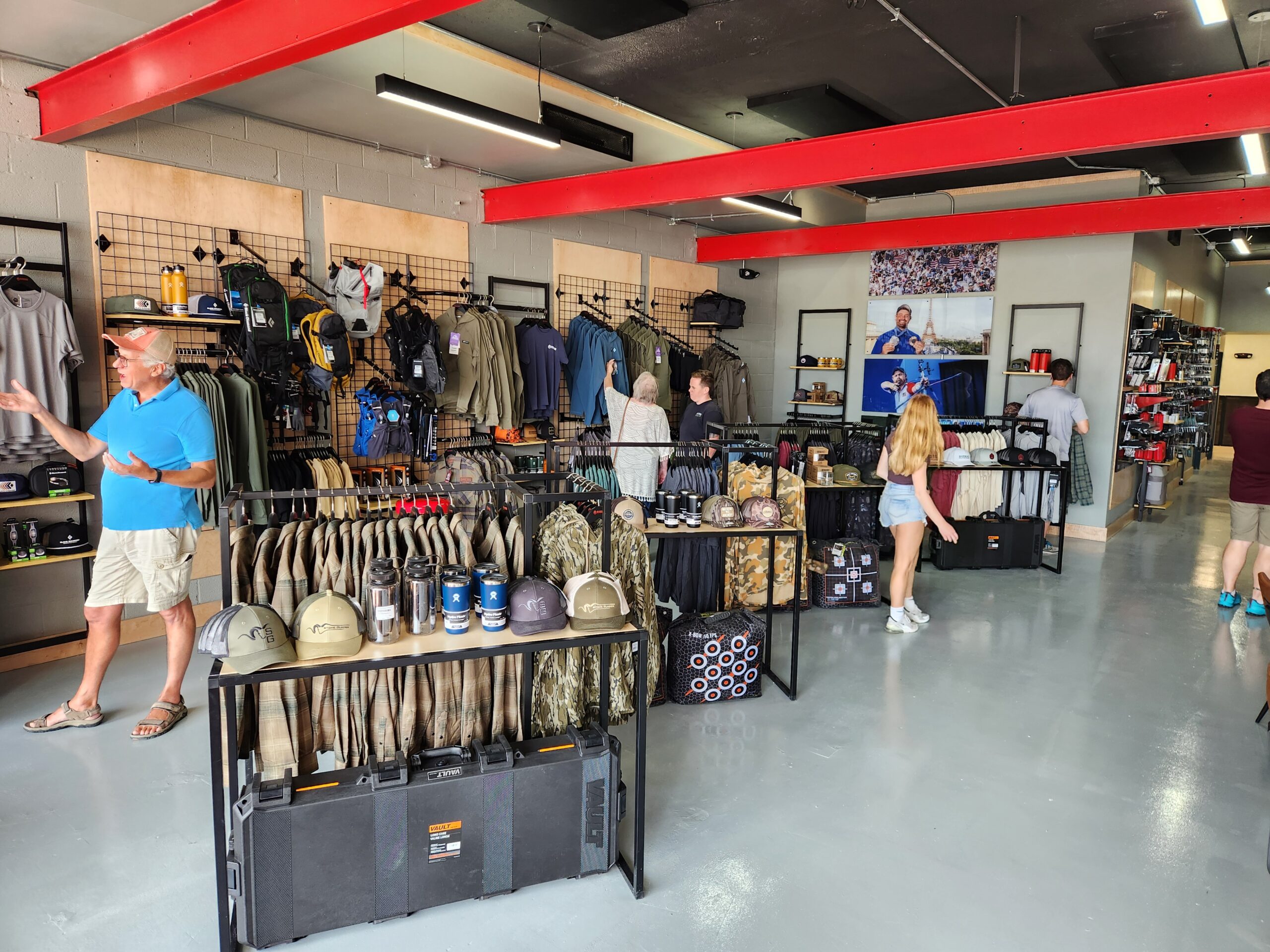 Shrewd Outdoors Grand Opening. Patrons walk around an open, brightly lit retail space filled with archery gear.