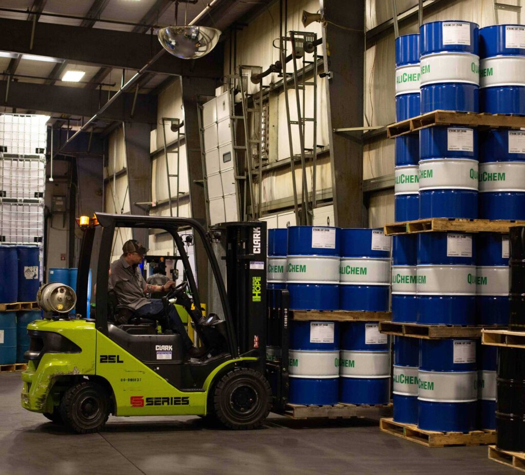White man uses a forklift to lift a pallet of barrels at QualiChem in Salem, Virginia.