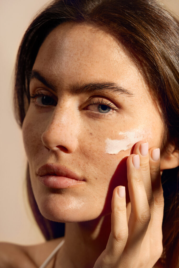 Image of a model posing for the camera while applying RINGANA sunscreen product on her face